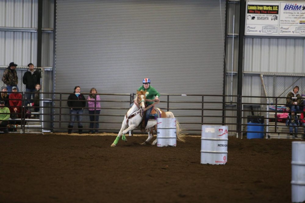 Horse and rider weave between barrels in the arena
