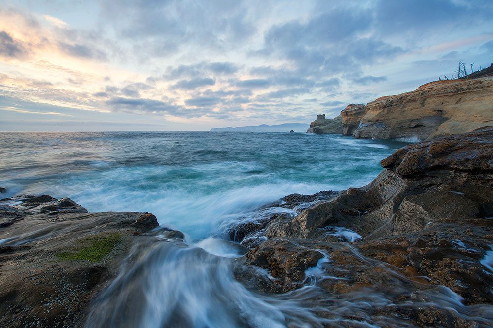 Clouds and waves in front of rocky cliffs
